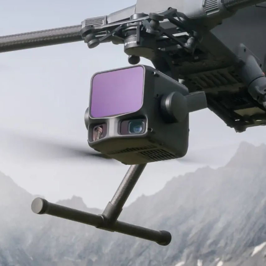 Eine Hand hält einen Drohnenquadrocopter vor einer Brücke.